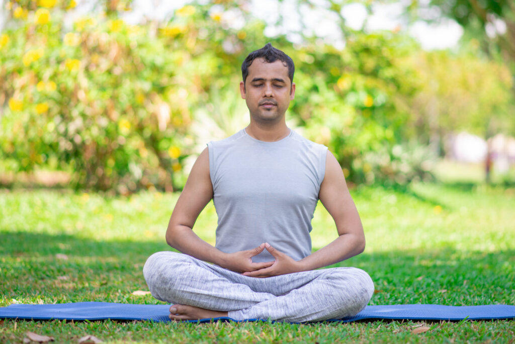 focused young indian man meditating in lotus pose